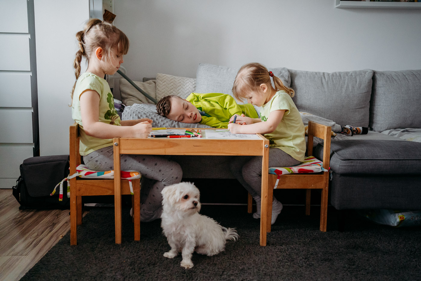 Dzieci rysują, obok siedzi pies maltańczyk, sesja rodzinna lifestylowa Łódź