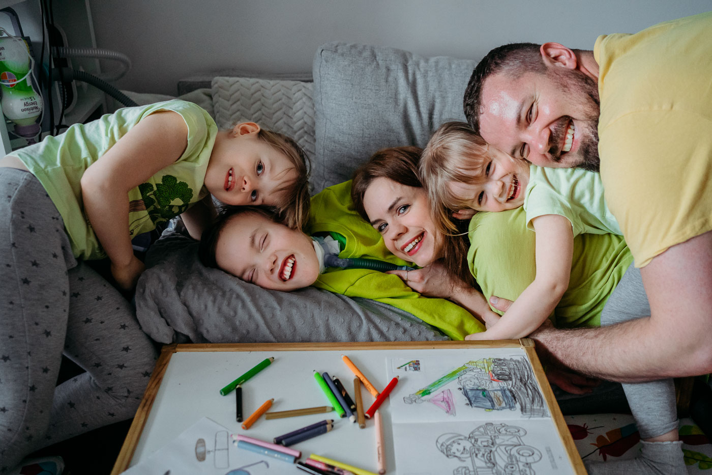 Kadr z rodzinnej sesji lifestylowej, rodzice z dziećmi wspólnie spędzają czas rysując
